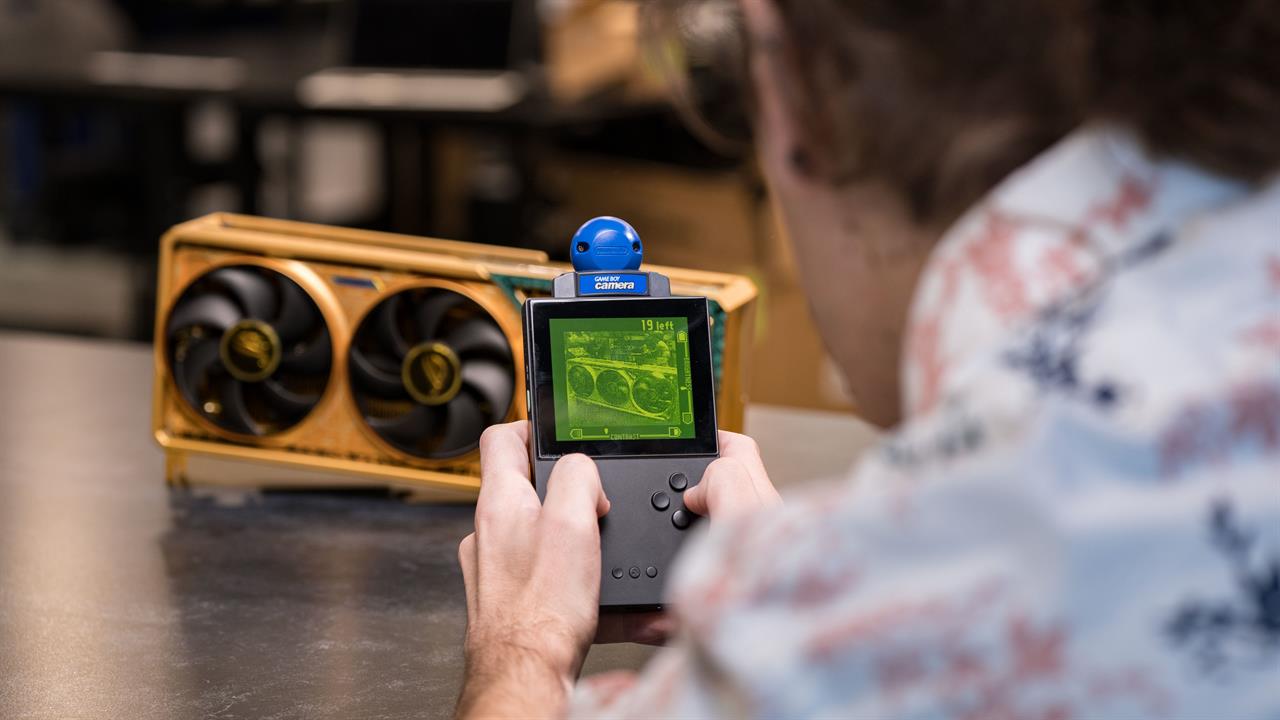 A photo of a person taking a picture of the 5090 Dhahab edition with a gameboy camera