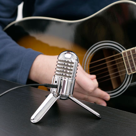 Close up of the Samson Metero microphone positioned by a hand playing a guitar 