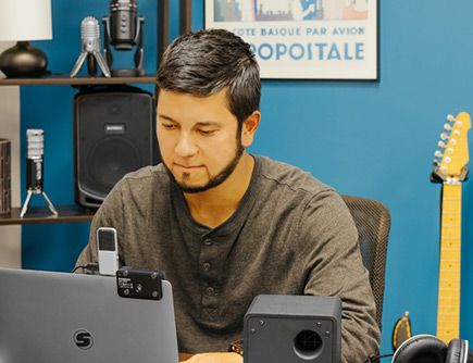 Guy looking at a laptop connected to the Samson Go Mic USB Condenser Microphone.