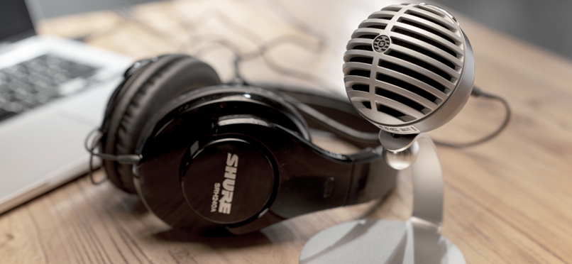 Shure SRH240A Professional Quality Headphones with Padded Headband & Ear Cups laying next to a microphone