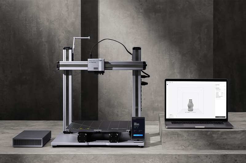 Snapmaker A350 3D printer next to a laptop displaying a model on the screen