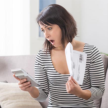 Woman with a shocked expression looking at a bill