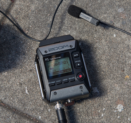 The Zoom F1 Field Digital Recorder resting on the pavement with lit display