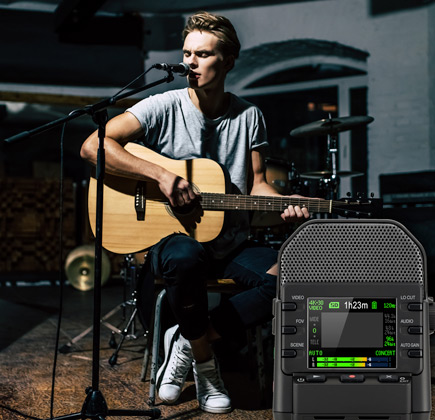 Guy playing an acoustic guitar with the The Zoom Q2n-4K video recorder filming his session