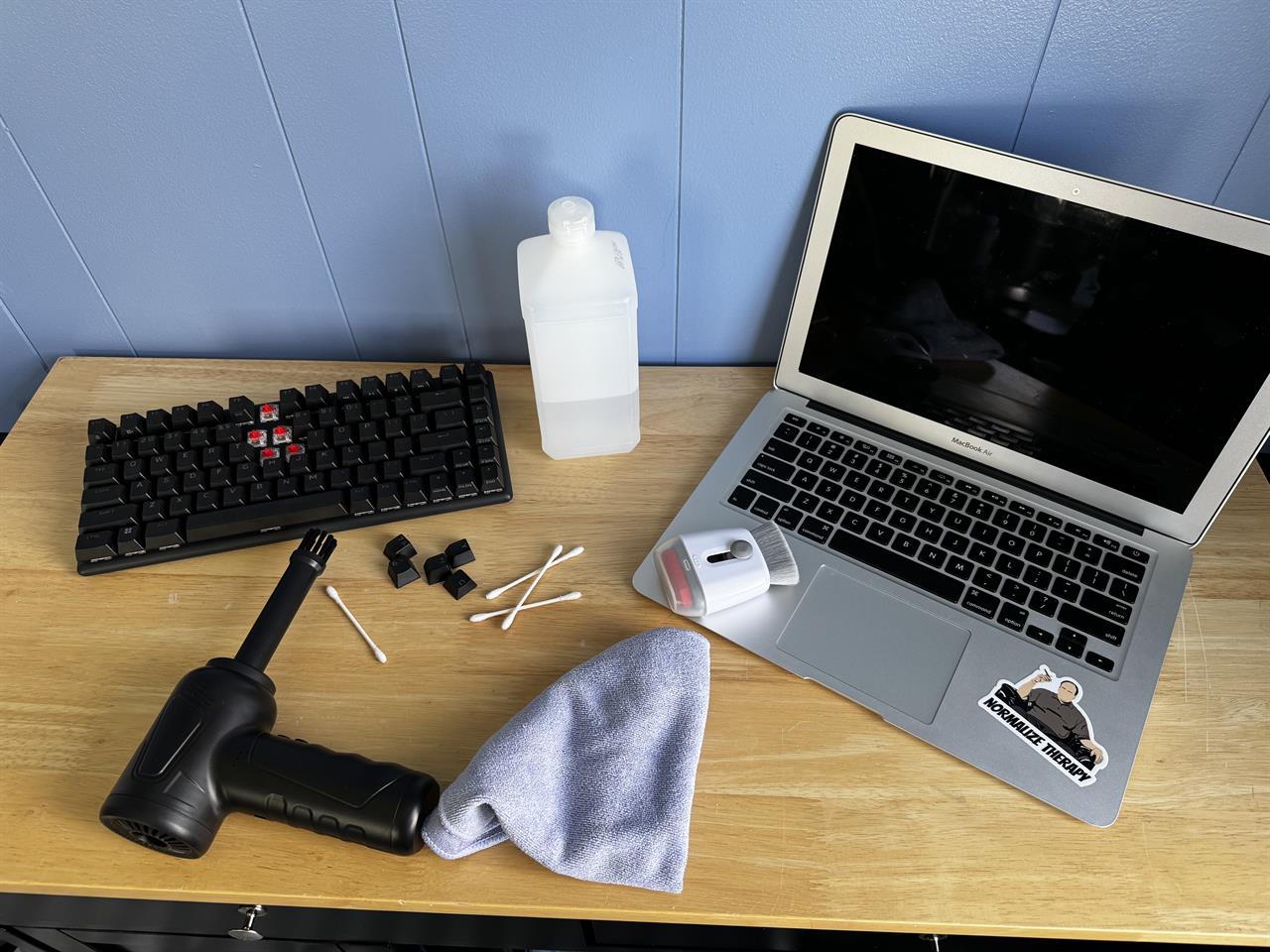 a macbook surrounded by cleaning supplies