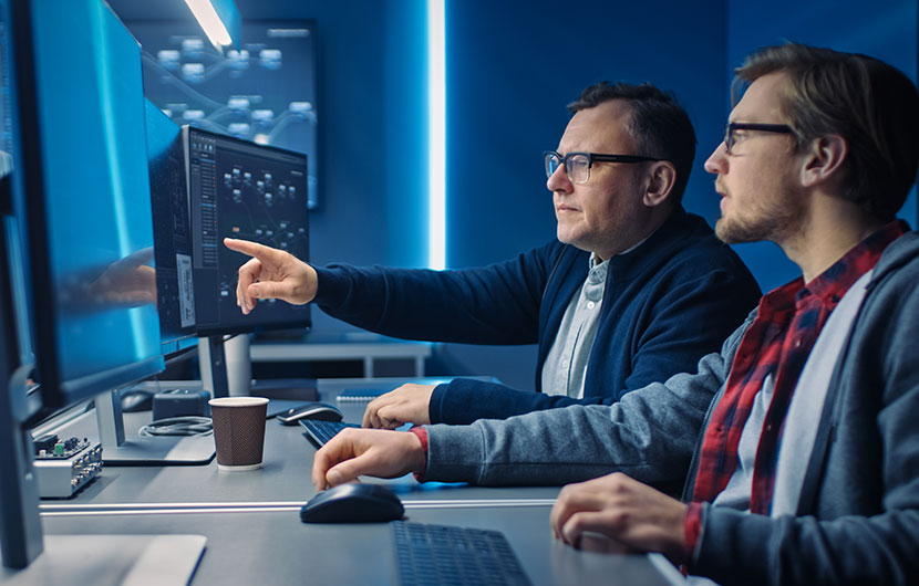 Two men conferring over computer screen